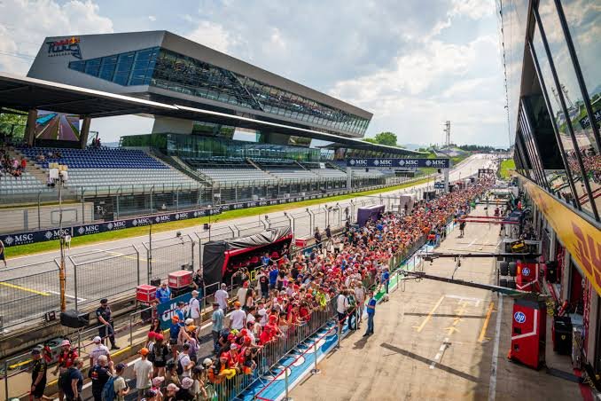 Formula 1 pit lane during race weekend 2026 — mechanics working on cars from 11 different constructors