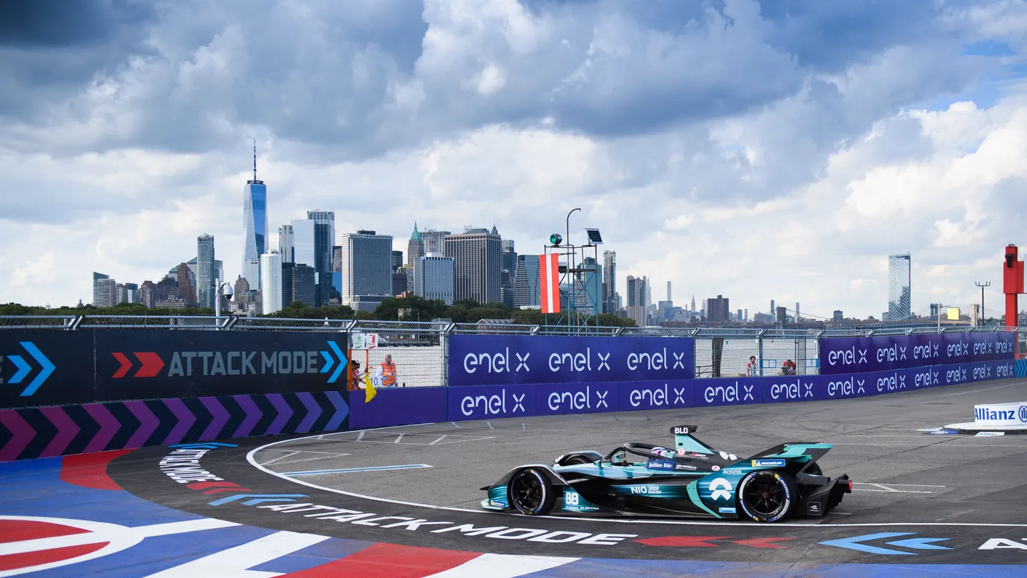 Formula E electric race cars racing through a tight city street circuit — Formula E championship action with papaya McLaren livery