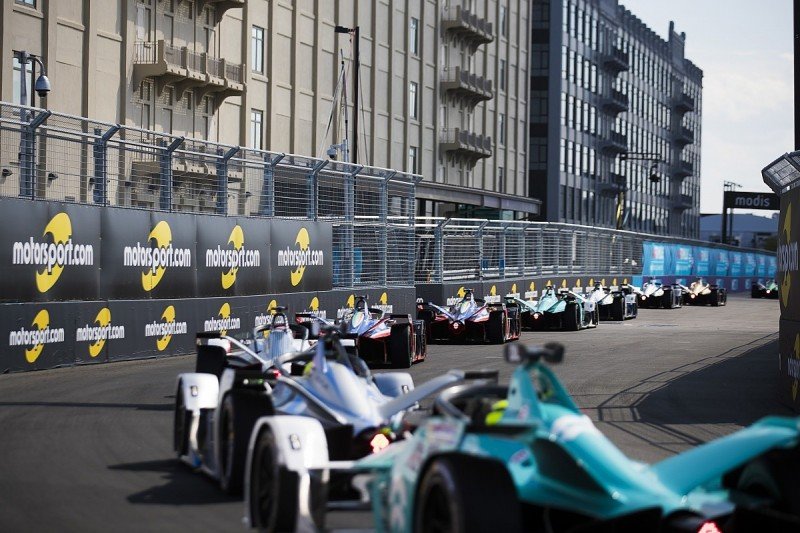 Formula E electric race cars battling for position on a tight street circuit corner during an E-Prix