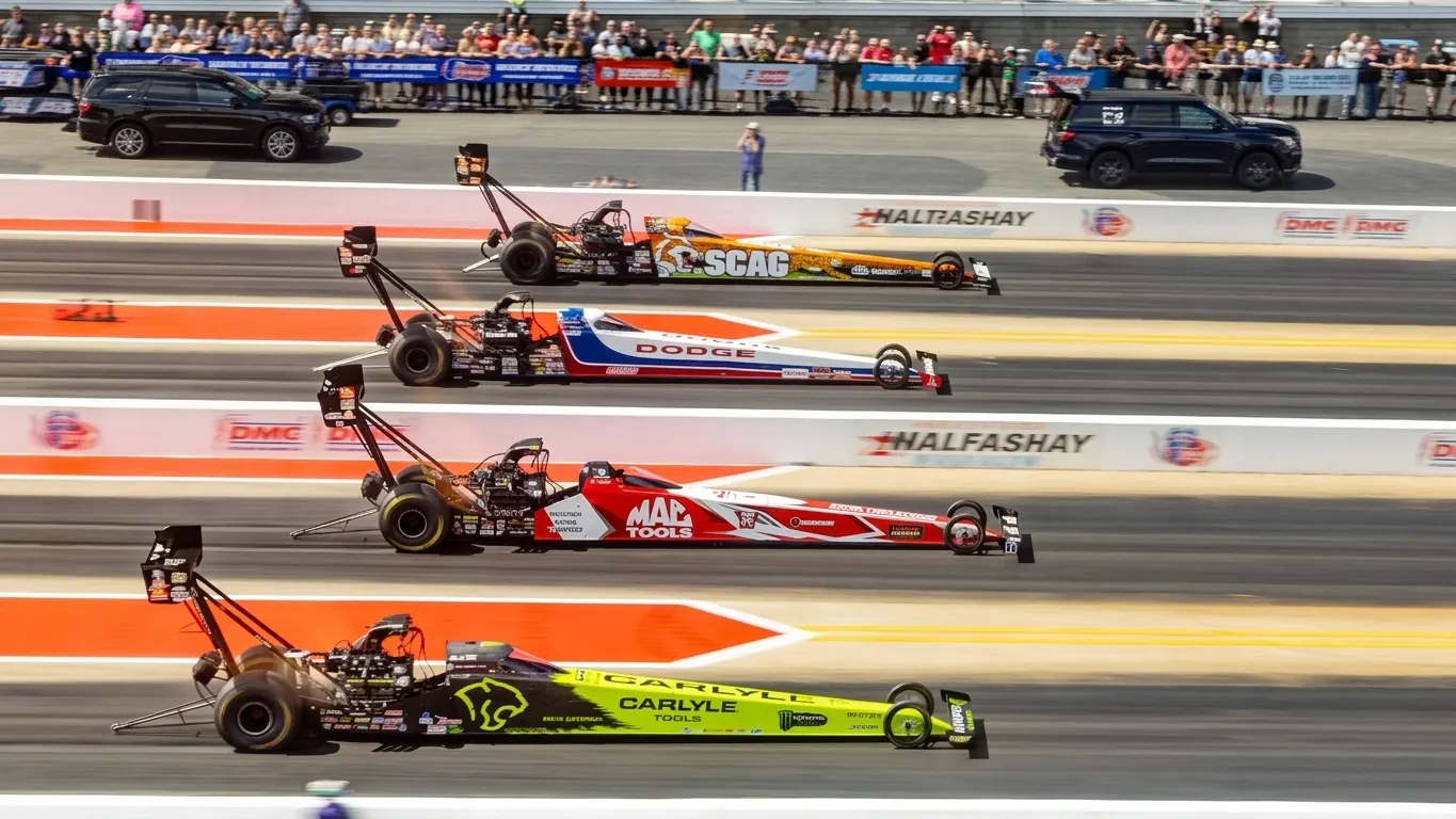 High-performance drag racing cars side by side on the starting line at a Four-Wide NHRA nationals event