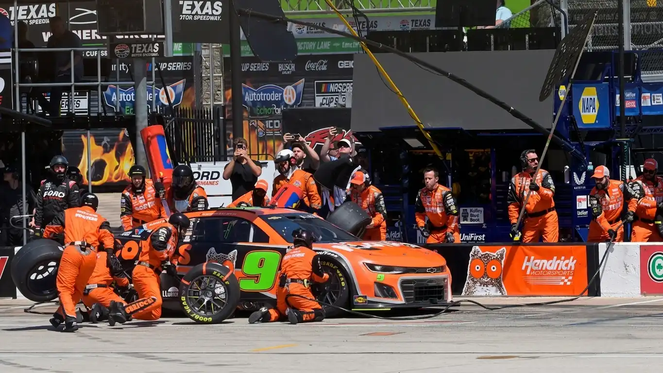 NASCAR pit crew performing a tyre change and fuel top-up during a green flag pit stop at a superspeedway
