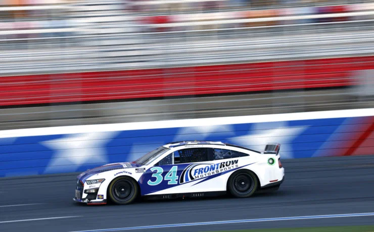 NASCAR Next Gen stock car at high speed on a superspeedway — the tapered spacer limits top speed to around 200 mph for safety