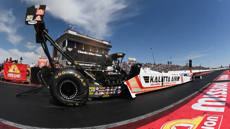 NHRA Top Fuel dragster at full power down the quarter mile with nitromethane exhaust flames visible