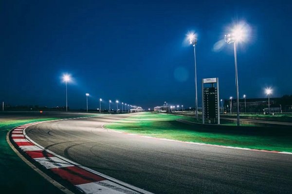 Modern racing circuit at night with bright floodlights illuminating the track — Shanghai E-Prix atmosphere 2026