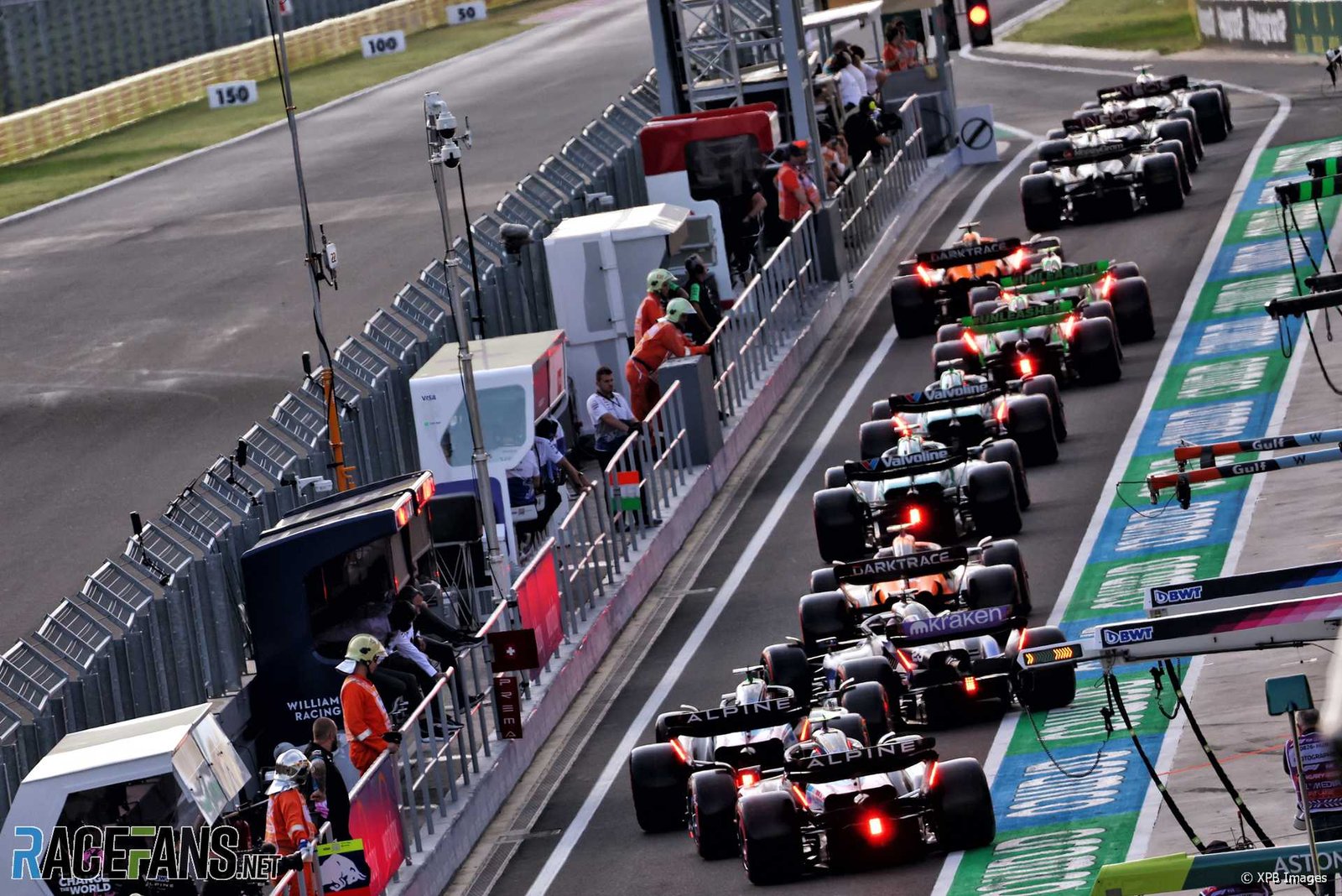 F1 pit lane during qualifying with multiple cars preparing for their timed runs