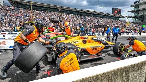 IndyCar pit stop with mechanics changing tyres during a road course race weekend