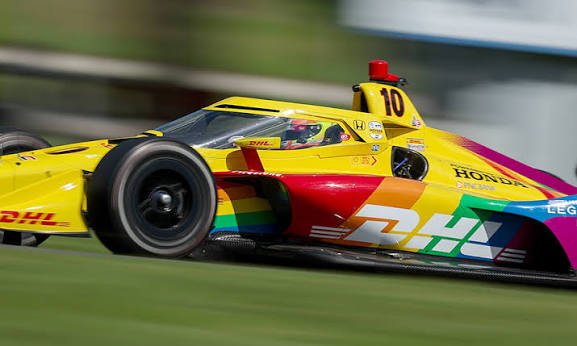 Open wheel race car at speed showing aerodynamic elements and the high-performance hybrid powertrain package