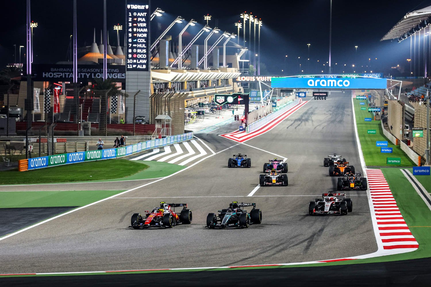 Formula 1 pit lane during race weekend with team garages and mechanics preparing cars for 2026 season