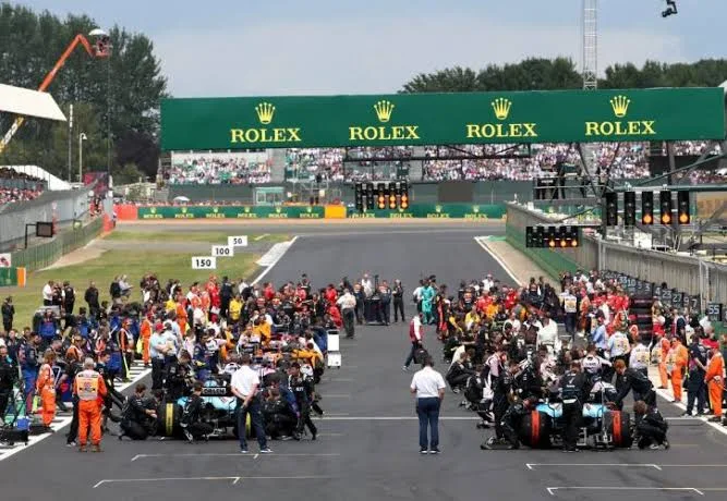 Formula 1 car pit stop showing mechanics changing tyres and refuelling — demonstrating the team infrastructure behind every F1 car