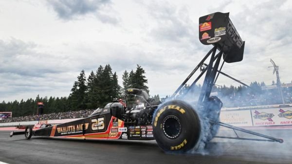 NHRA drag racing cars lined up in pit lane at a national event showing team sponsor liveries and crew preparation