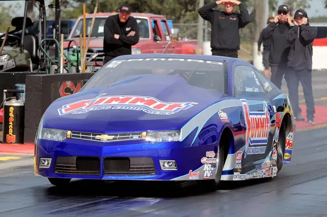 Pro Stock drag racing car launching from the starting line with front wheels lifted off the track