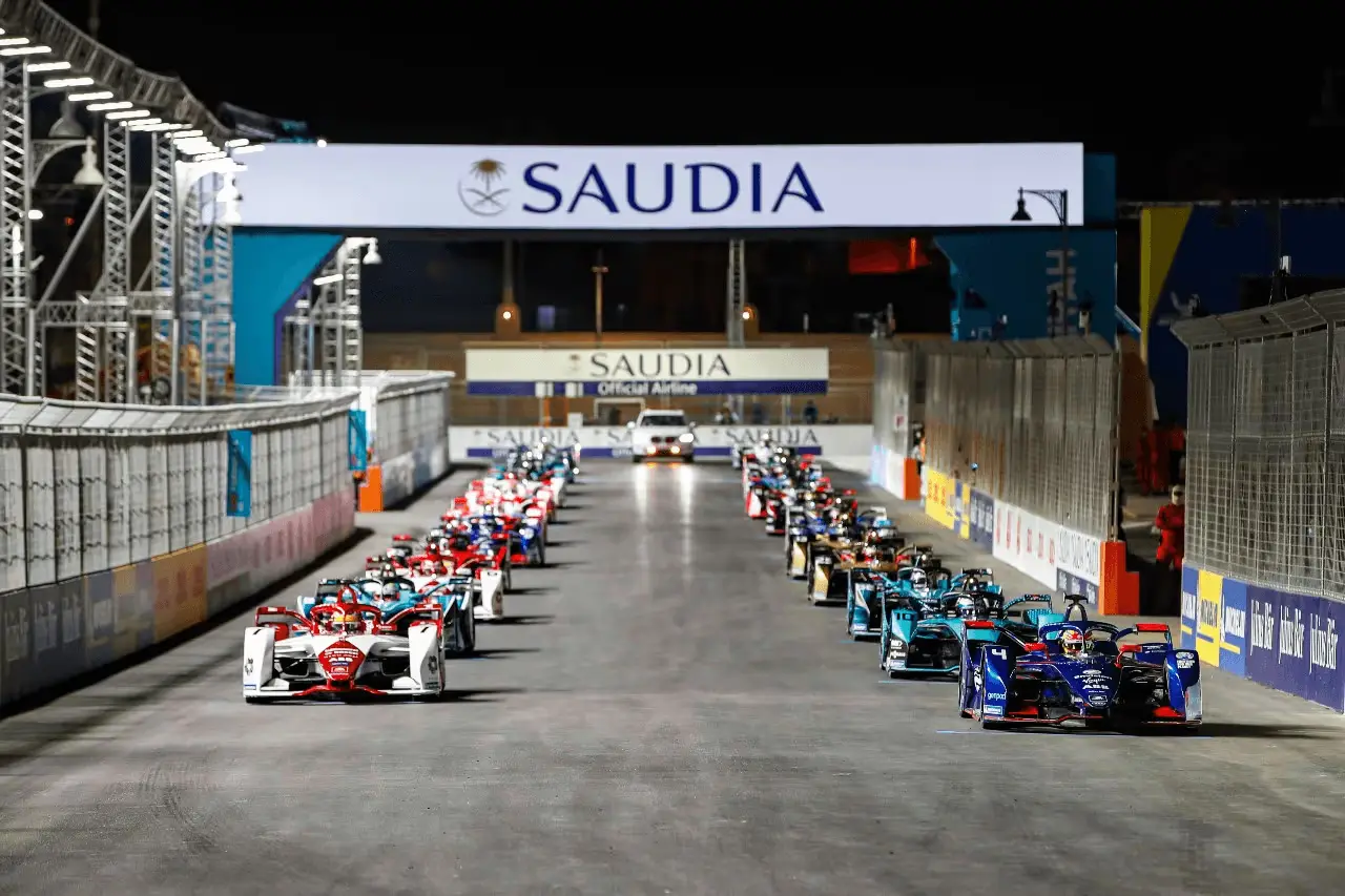 Electric racing car on a street circuit at night with city lights in background representing Formula E Gen4 era