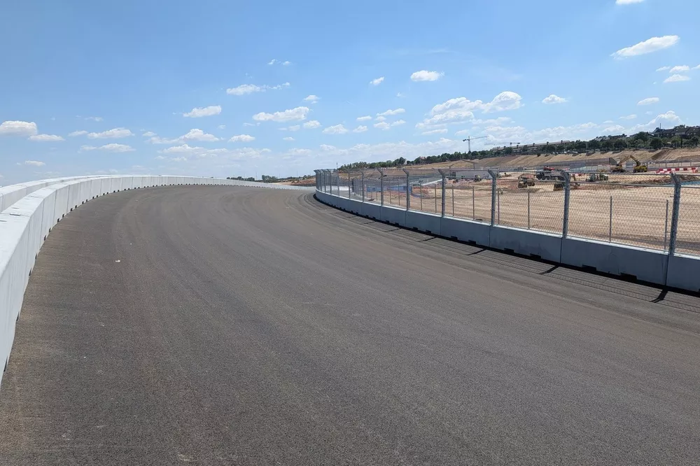 Formula 1 car testing on a new circuit with grandstands and city skyline in the background