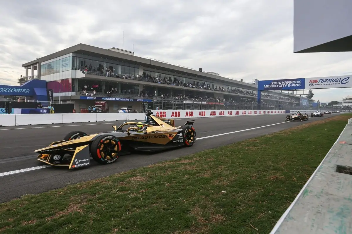 Formula E race car on a tight street circuit corner — barriers close, city backdrop
