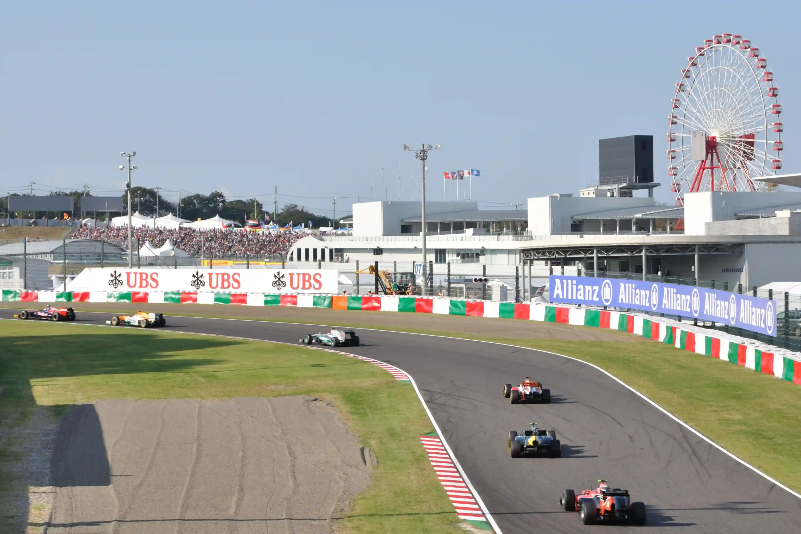 Formula 1 field accelerating from staggered grid positions at the 2012 Japanese Grand Prix