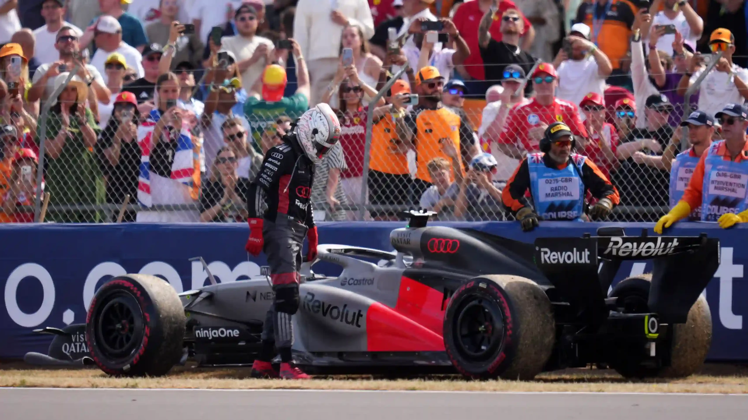 Nico Hulkenberg stands beside his stopped Audi during the 2026 British Grand Prix
