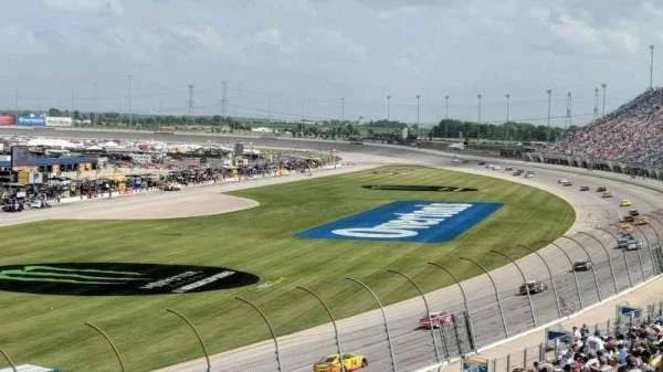 Packed NASCAR grandstands at a 1.5-mile oval race venue with thousands of fans attending the event
