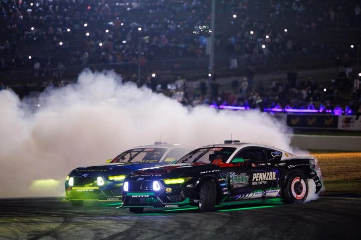 James Deane and Vaughn Gittin Jr drifting side by side under lights at a Formula DRIFT event