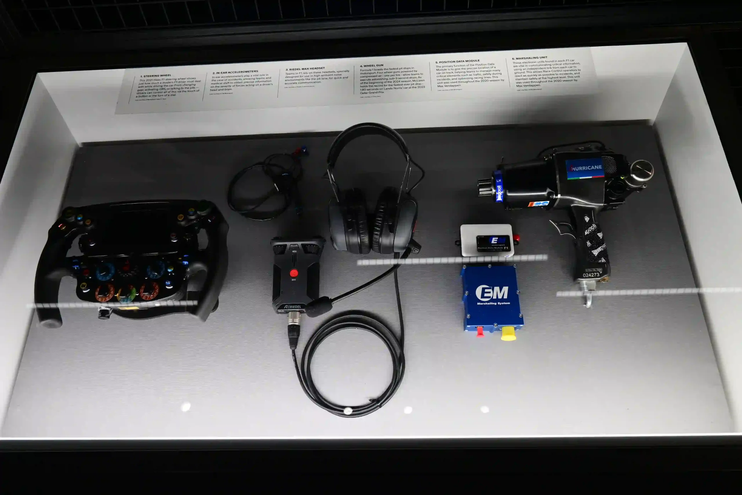 Formula 1 exhibition display containing a pit wall headset, steering wheel and race equipment