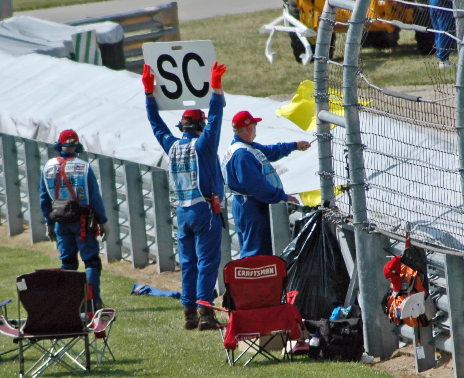 Formula 1 marshal waving a yellow flag beside an SC Safety Car board at the 2005 United States Grand Prix