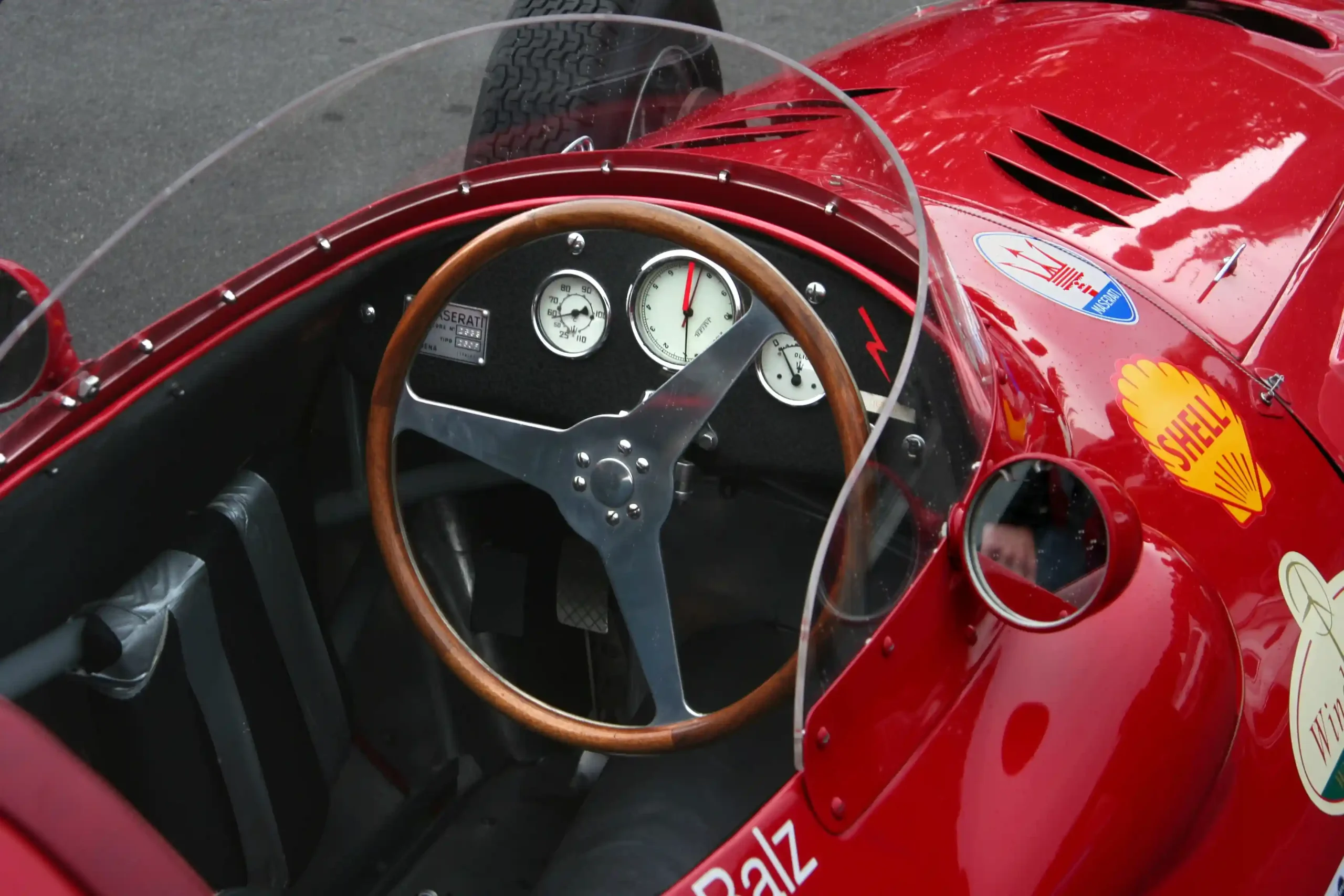 Historic Maserati 250F cockpit with a large round steering wheel and analog dashboard