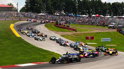 Open-wheel race car through tight road course corners — representing Mid-Ohio Sports Car Course 2026 IndyCar challenge