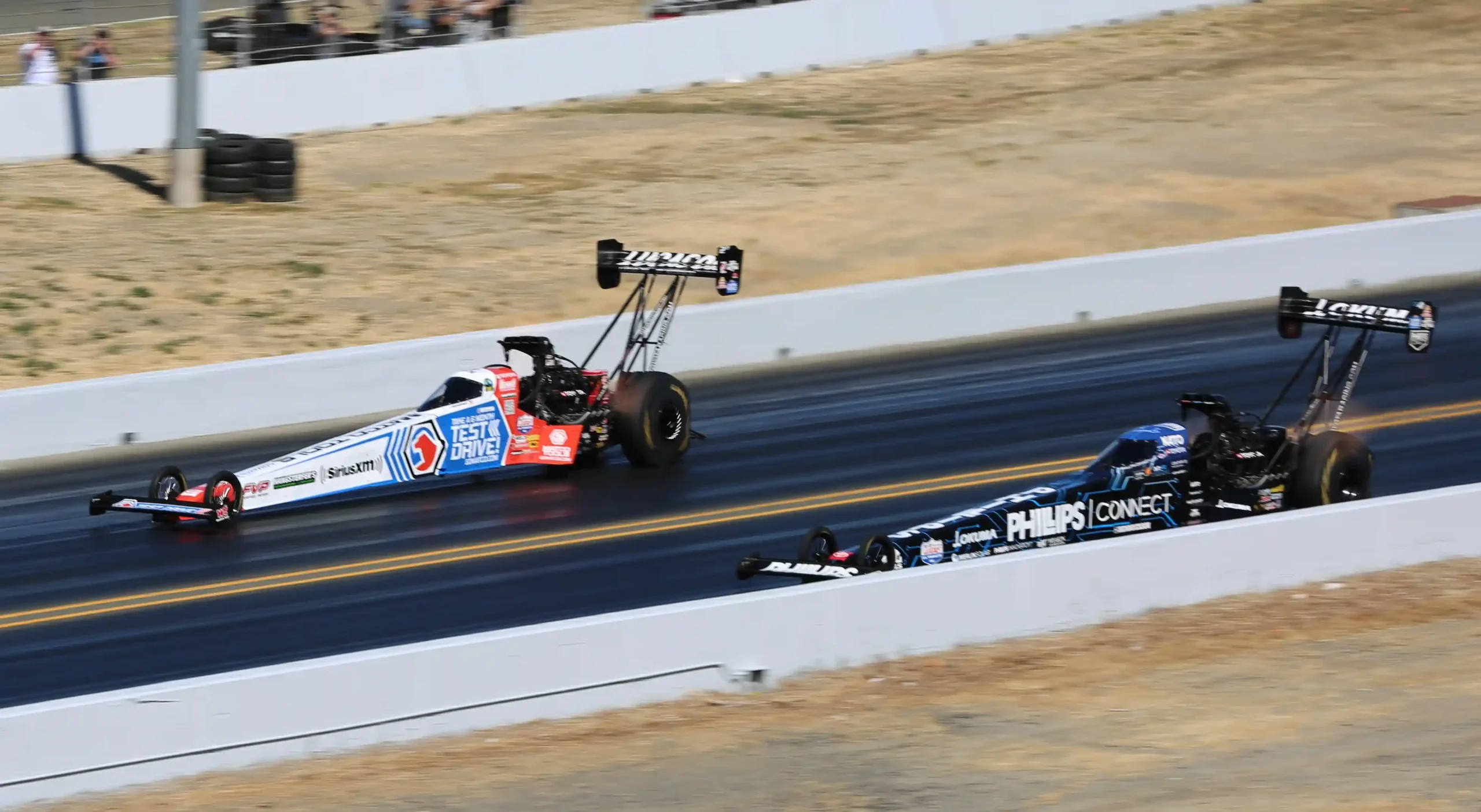 Two NHRA Top Fuel dragsters accelerating side by side at Sonoma Raceway