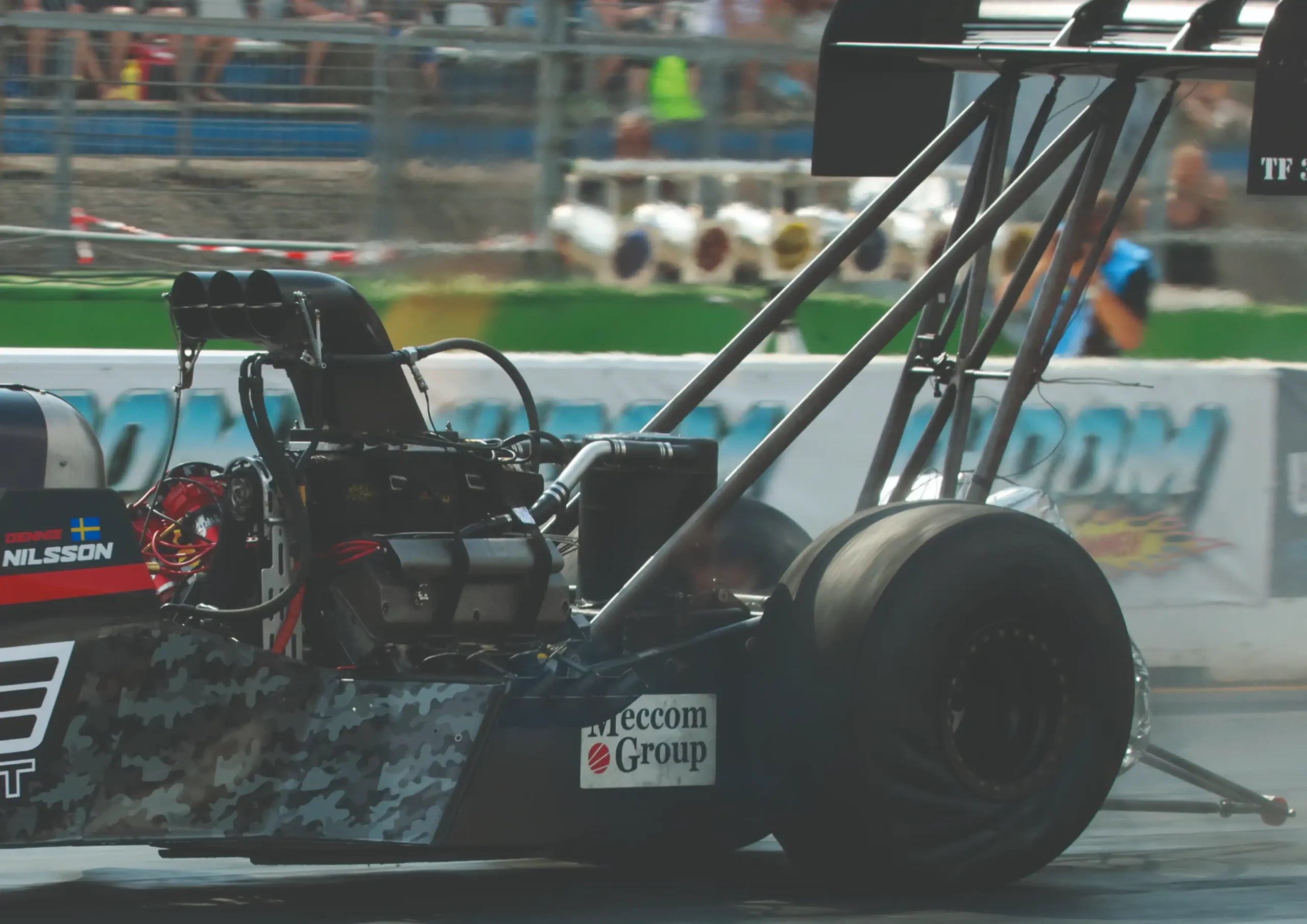 Close view of a supercharged Top Fuel V8 engine with large intake scoop, ignition components and exhaust headers