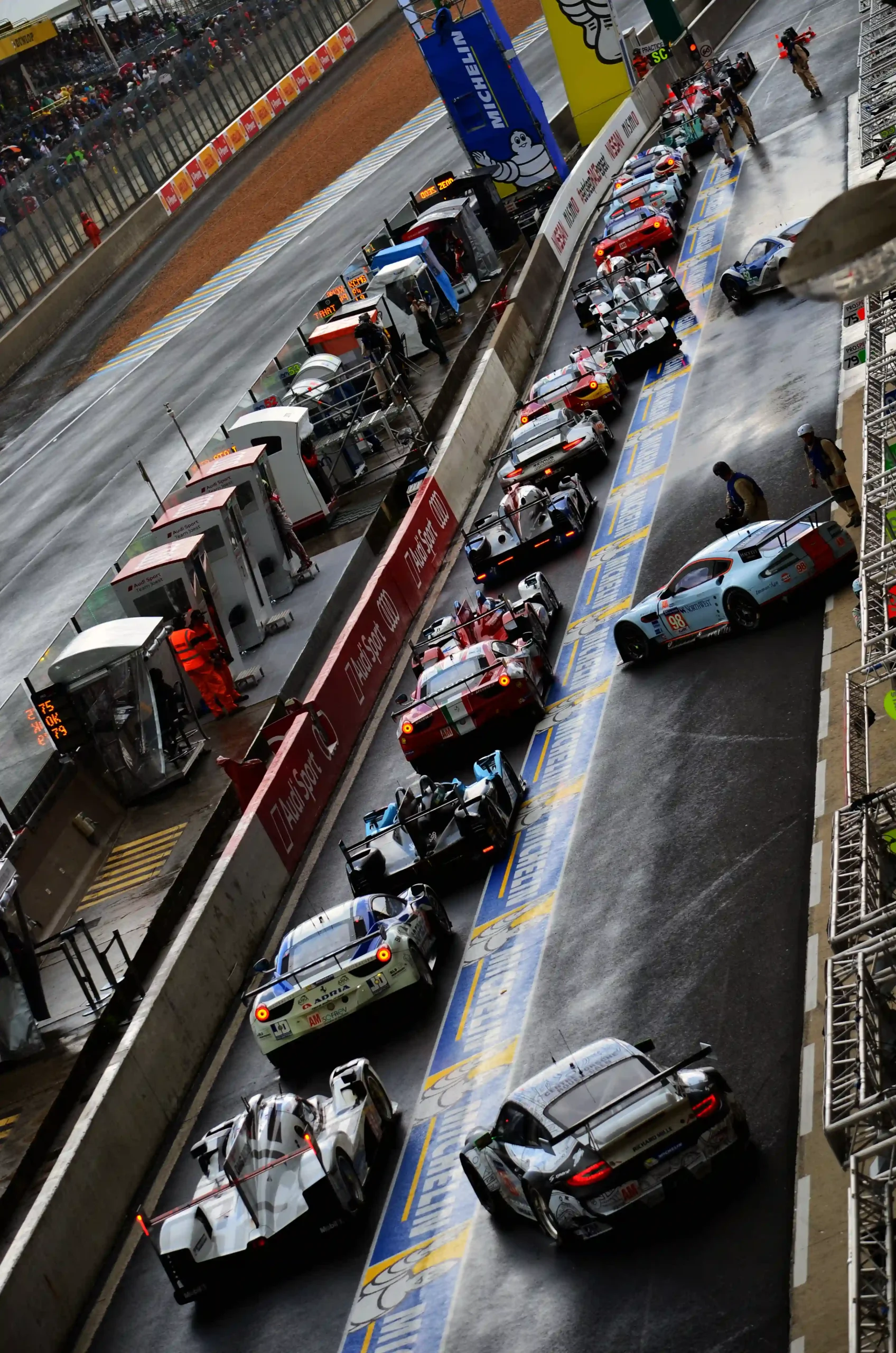 Race cars held in a pit lane queue while waiting for a safe release