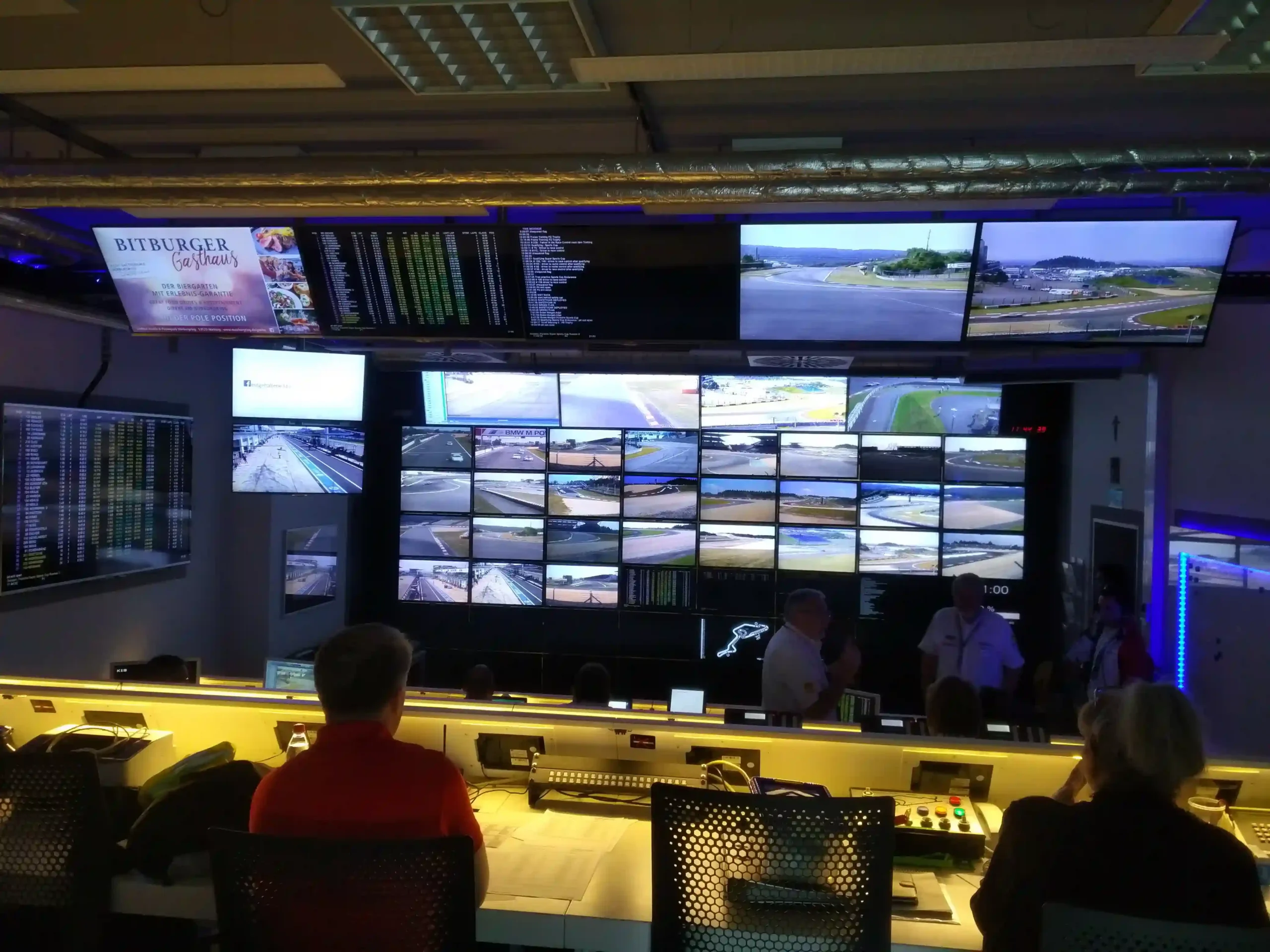 A motorsport race control room at the Nürburgring with timing and camera screens