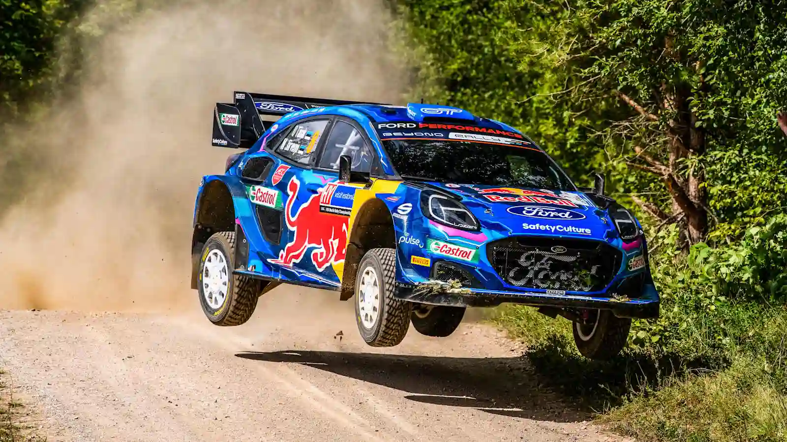Ott Tänak powering a rally car through a narrow forest gravel stage at WRC Rally Estonia