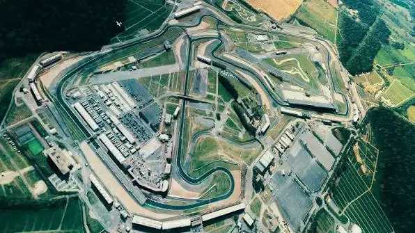 Open-wheel racing car cornering at high speed on a British racing circuit with packed grandstands