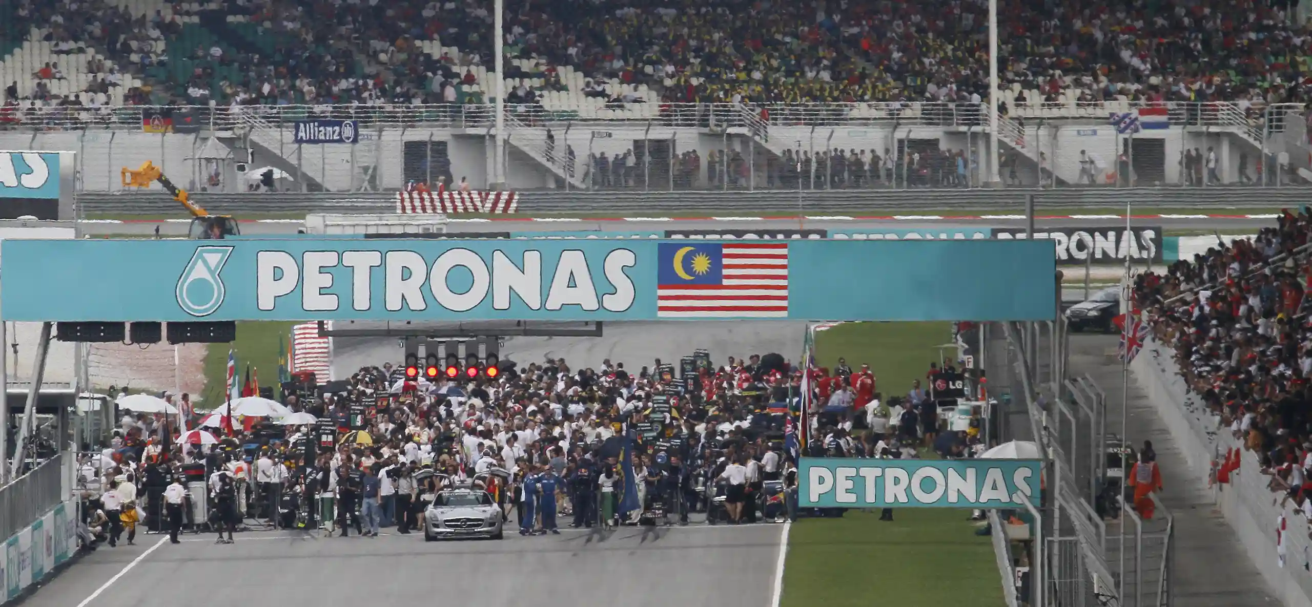 Formula 1 cars and team personnel assembled on the starting grid at the 2010 Malaysian Grand Prix