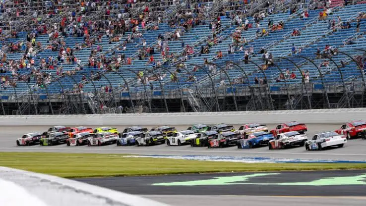 Stock cars racing in tight formation on a high-banked 1.5-mile intermediate oval — representative of Chicagoland Speedway racing