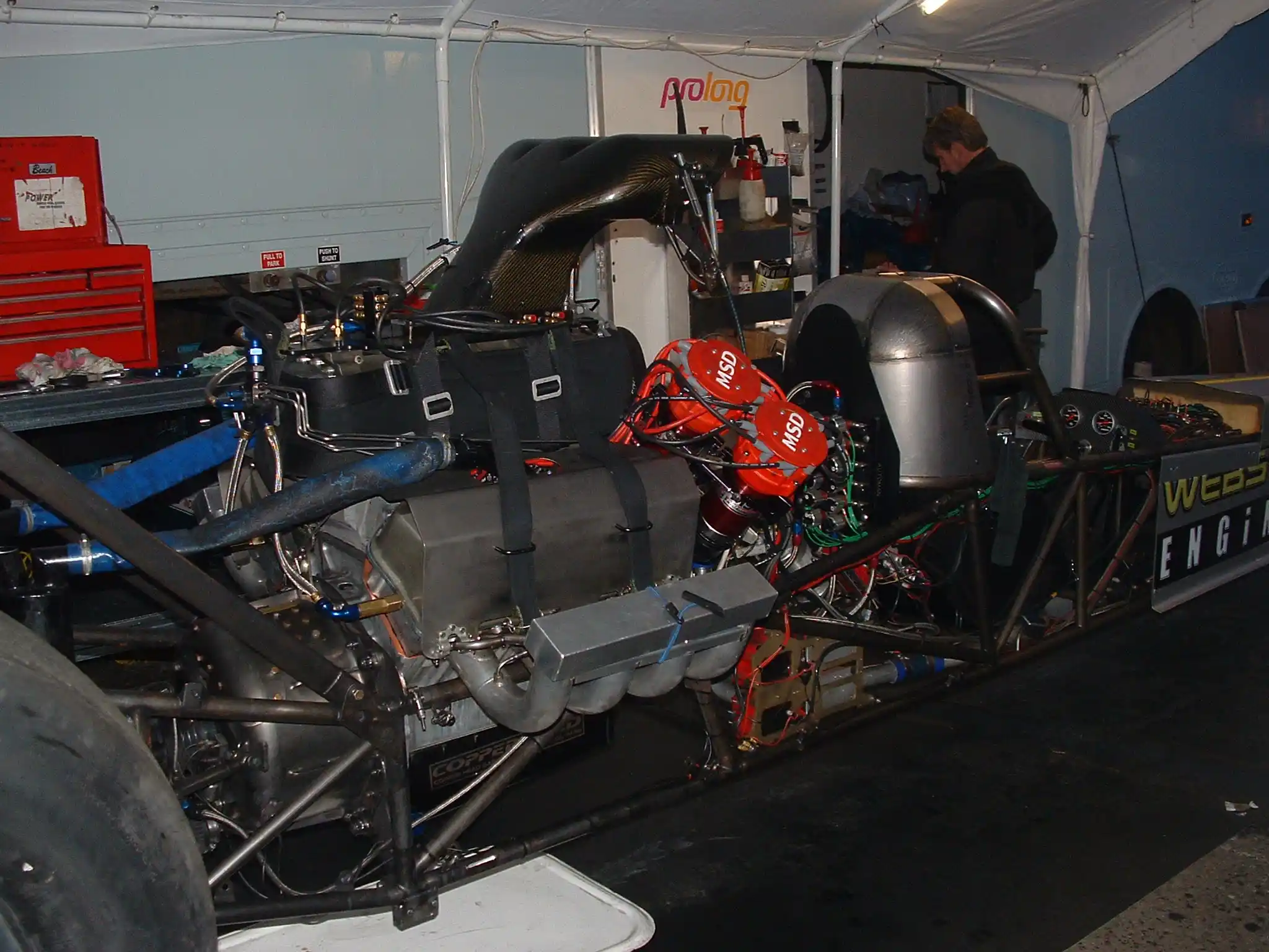 Exposed Top Fuel drag racing engine in the pits showing supercharger, injector and exhaust headers