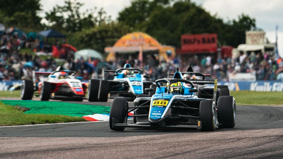 British F4 single-seaters racing at Thruxton in front of the spectator bank