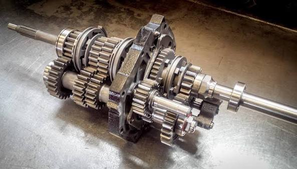 Technical close-up of racing gearbox internals showing straight-cut dog teeth and selector components used in sequential transmissions