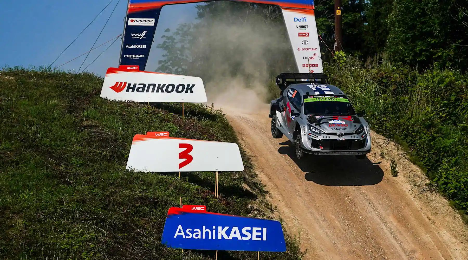 Toyota GR Yaris Rally1 attacking a high-speed gravel crest beneath the Visit Estonia arch during WRC Rally Estonia