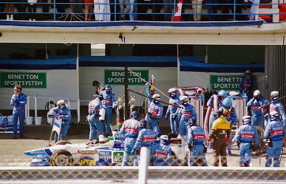 Jean Alesi and the Benetton Formula 1 pit crew during a pit stop at the 1996 Portuguese Grand Prix